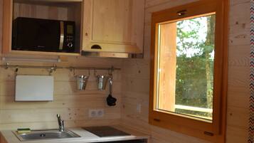 A compact kitchen with wooden cabinets, a microwave, a sink, a dishwasher, and a window.