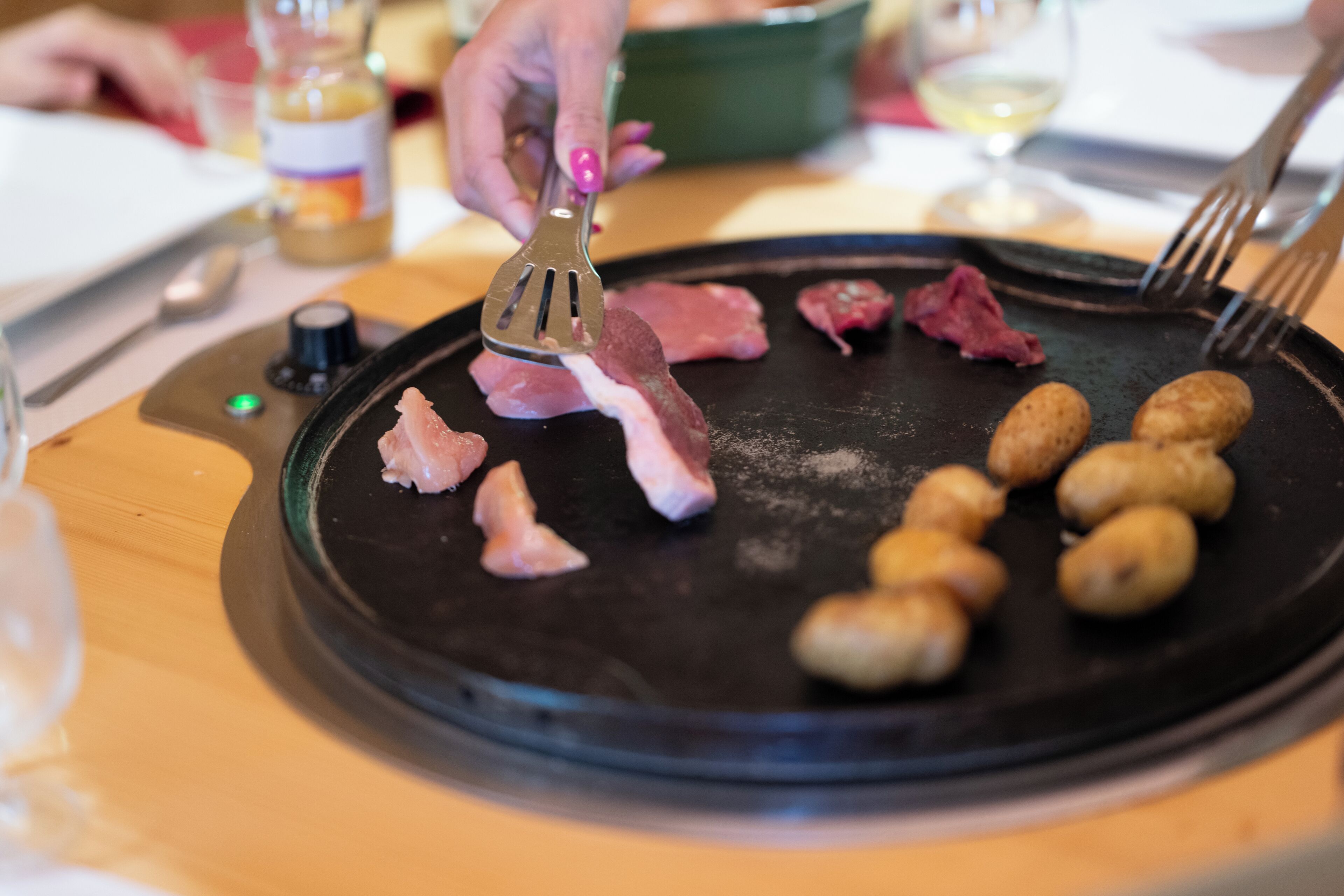 Jemand bereitet Fleisch und Kartoffeln auf einem Grill zu.
