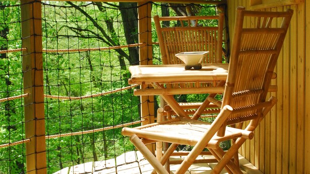A wooden deck with a table and chairs, surrounded by a wooden fence and trees. - Le Parc de la Belle (Magné)