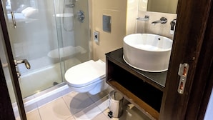 A modern bathroom with a glass-enclosed shower, a white toilet, and a large sink with a mirror above it. - LHA Paddington (London)