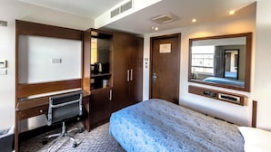 A hotel room with a bed, a desk with a chair, a wardrobe, a mirror, and a window. - LHA Paddington (London)