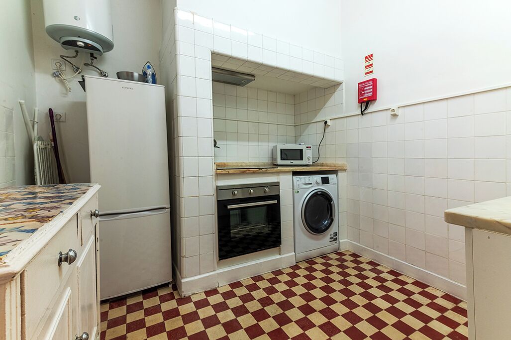 A compact kitchen with a refrigerator, microwave, oven, and washing machine.
