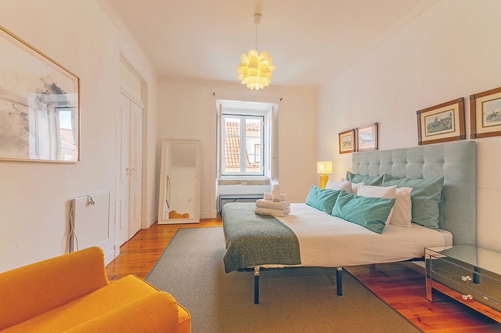 A bedroom with a bed, bedside table, lamp, and a window with curtains.