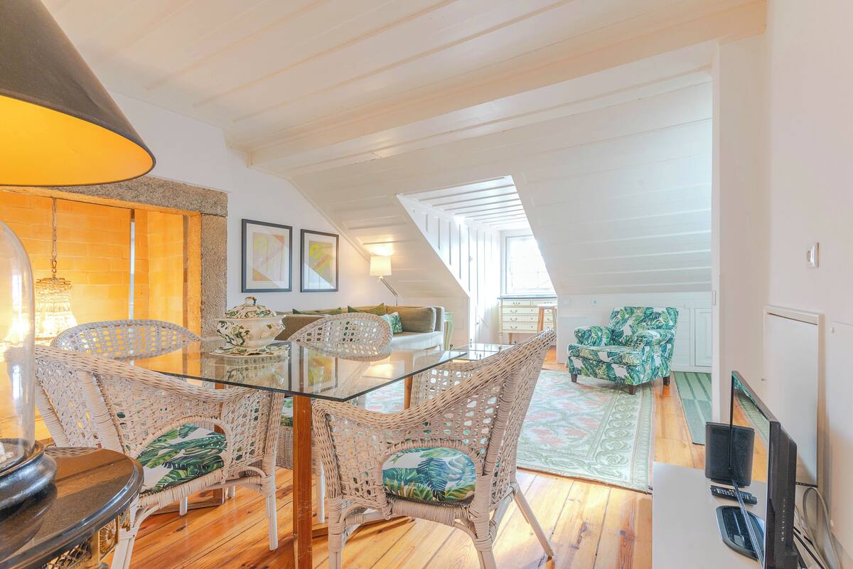 A dining area with wicker chairs, a glass table, and a lamp.