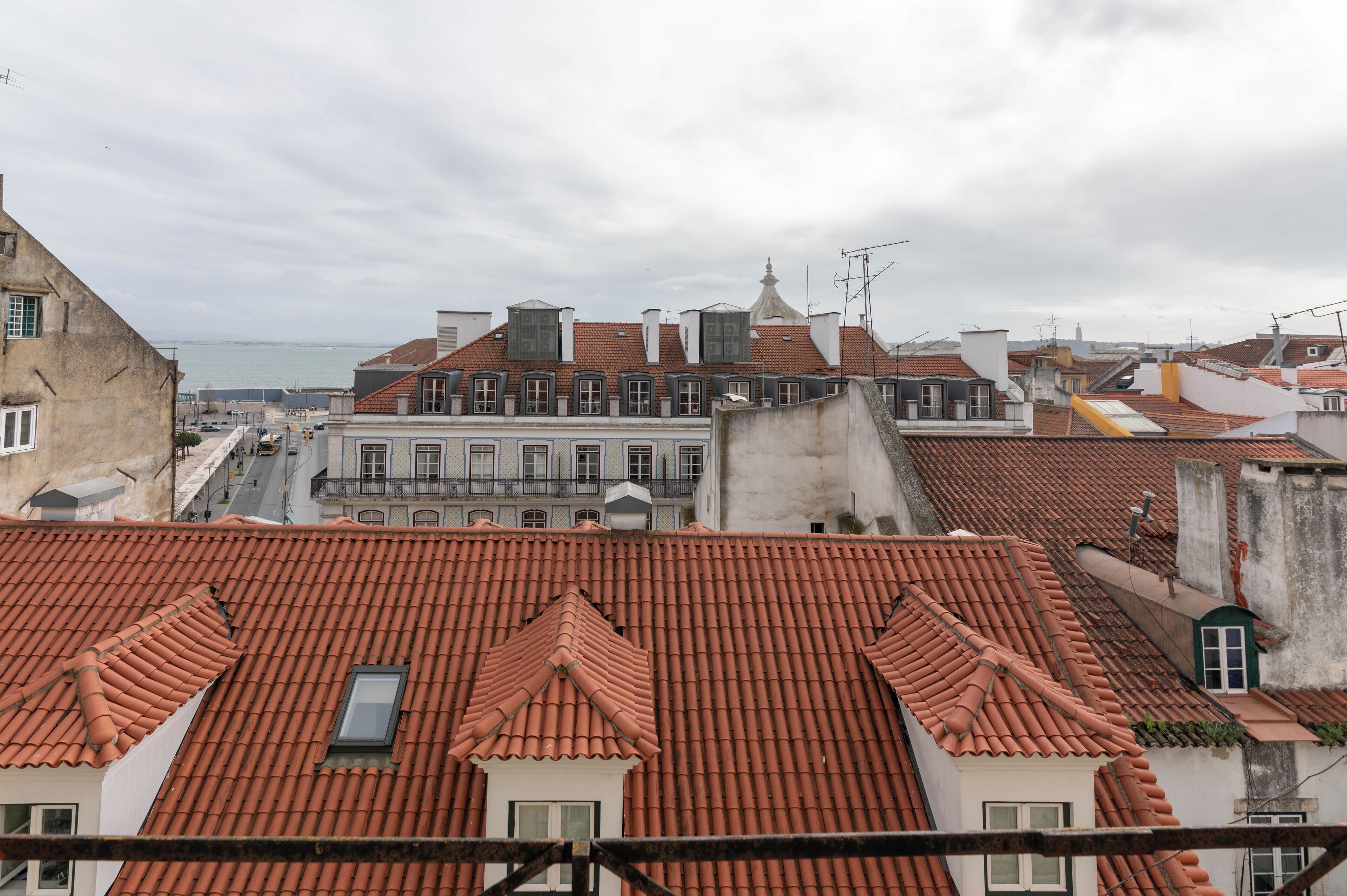 Blick auf terrakotta-gedeckte Dächer mit einer Mischung verschiedener Baustile, darunter ein markantes Gebäude mit Gründach und Balkon.