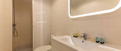 A bathroom with a shower, toilet, sink, and mirror.