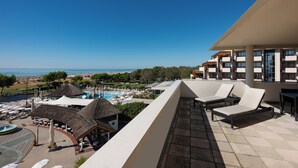 Une terrasse sur le toit, dotée de chaises longues, qui offre une vue sur une piscine et une plage.