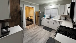 A modern kitchen with white cabinets, a stainless steel refrigerator, a gas stove, and a built-in oven.