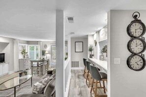 Une cuisine moderne avec un coin repas, un bar et un espace détente comprenant un canapé et des fauteuils.