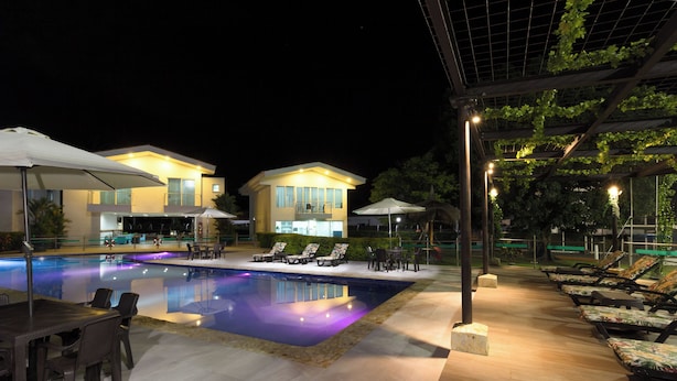 A swimming pool with lounge chairs and umbrellas, surrounded by buildings with balconies. - EL PARAISO HOTEL CAMPESTRE (La Virginia)