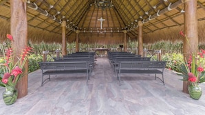 A covered outdoor area with benches arranged in rows, a central altar, and decorative plants. - EL PARAISO HOTEL CAMPESTRE (La Virginia)