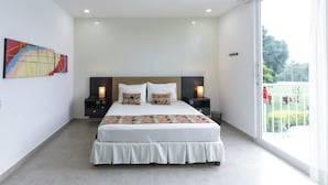 A modern bedroom with a large bed, two bedside tables, and a view of a balcony. - EL PARAISO HOTEL CAMPESTRE (La Virginia)