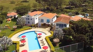 A hotel with a swimming pool, multiple guest rooms, and a lush green landscape in the background. - EL PARAISO HOTEL CAMPESTRE (La Virginia)