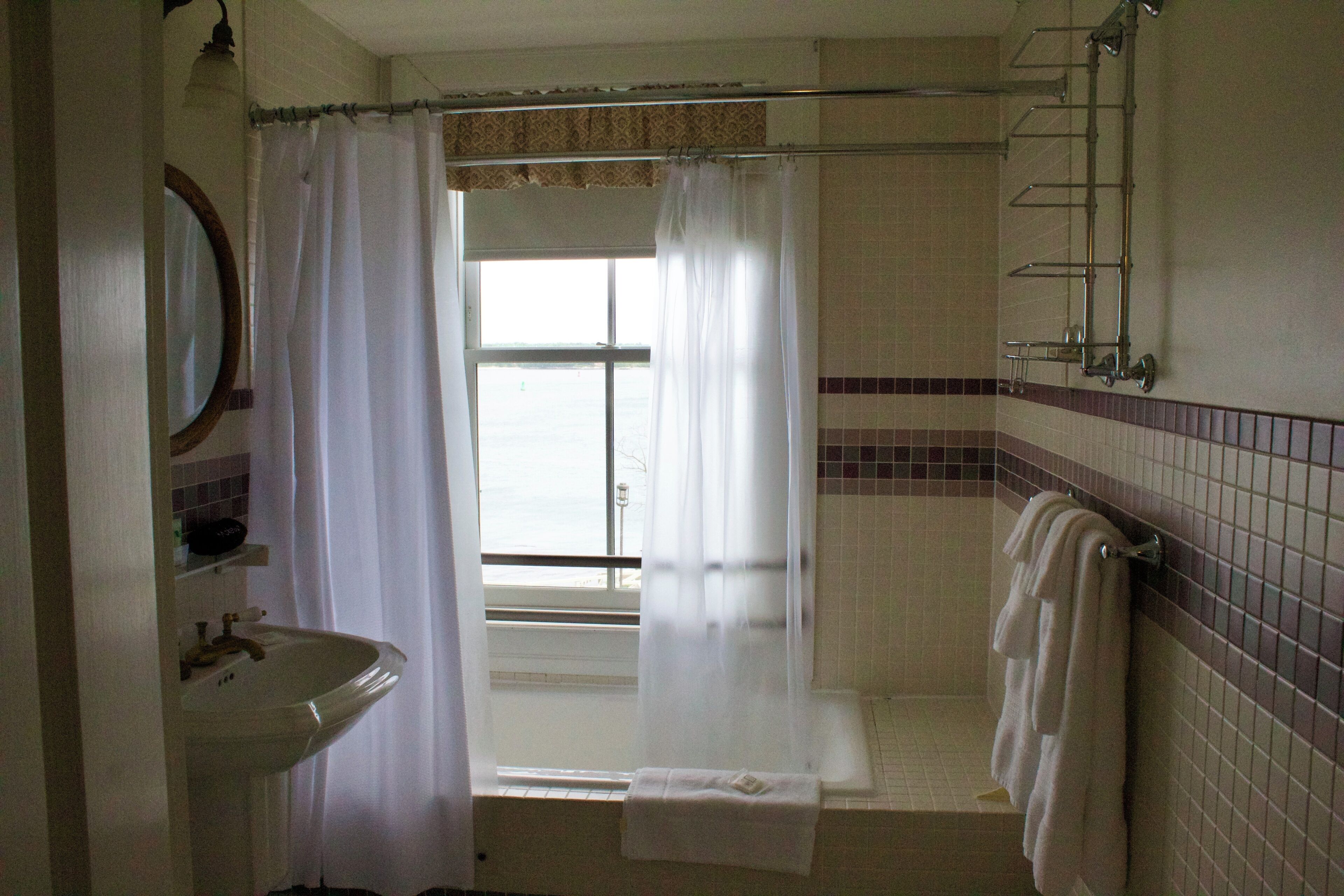 A bathroom with a sink, a shower with a curtain, and a bathtub with towels.