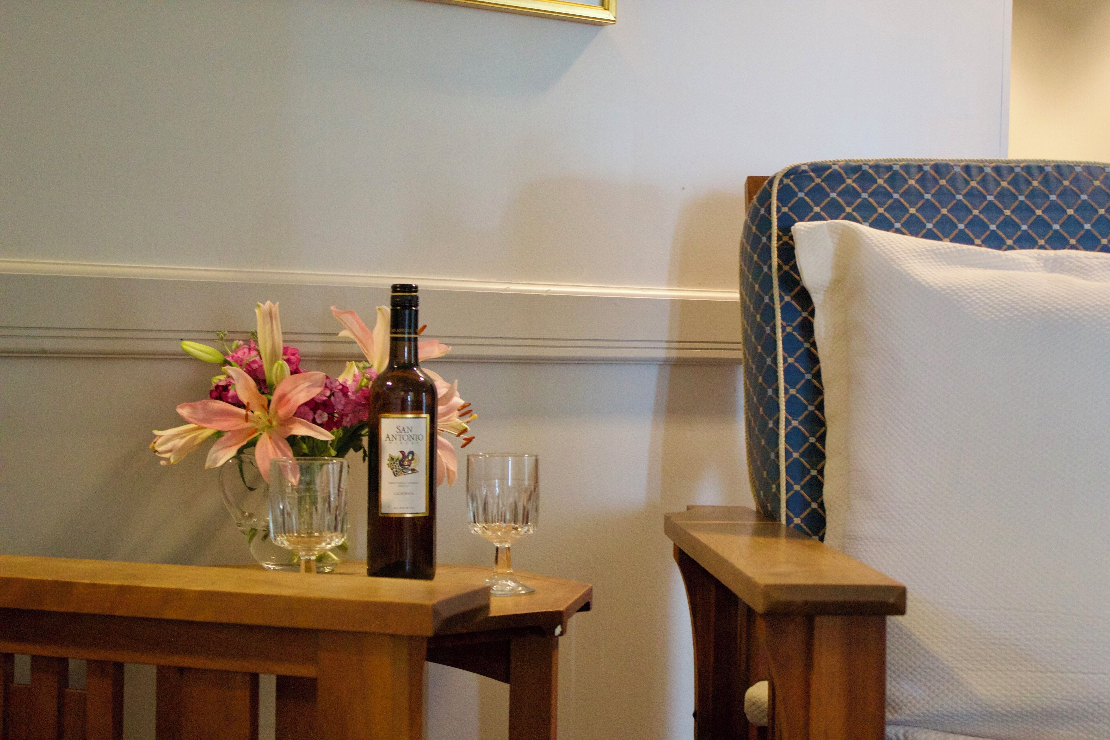 Une table en bois avec une bouteille de vin, un verre et un vase de fleurs.