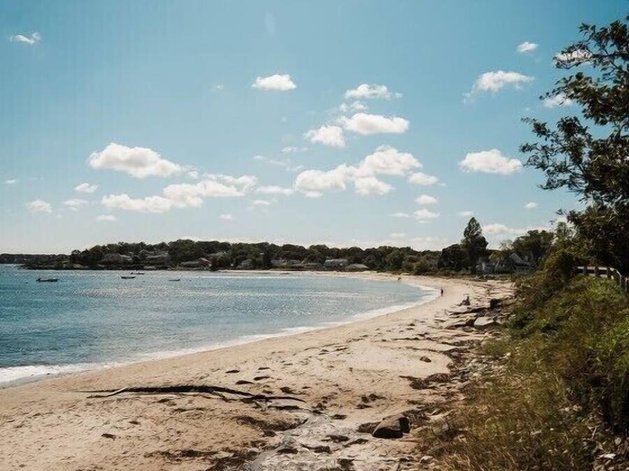 A beach with a sandy shore, calm water, and a clear sky.