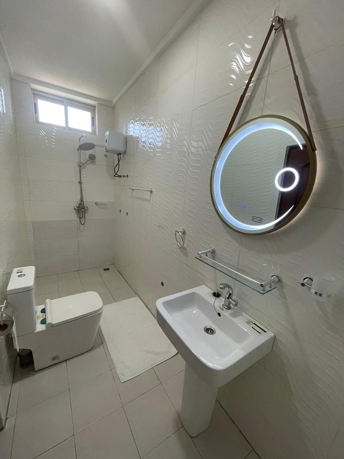 A modern bathroom with a toilet, sink, and shower.