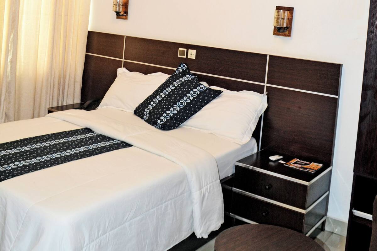 Une chambre d’hôtel comprenant un lit, des tables de chevet, un appareil de climatisation et une petite table ronde.