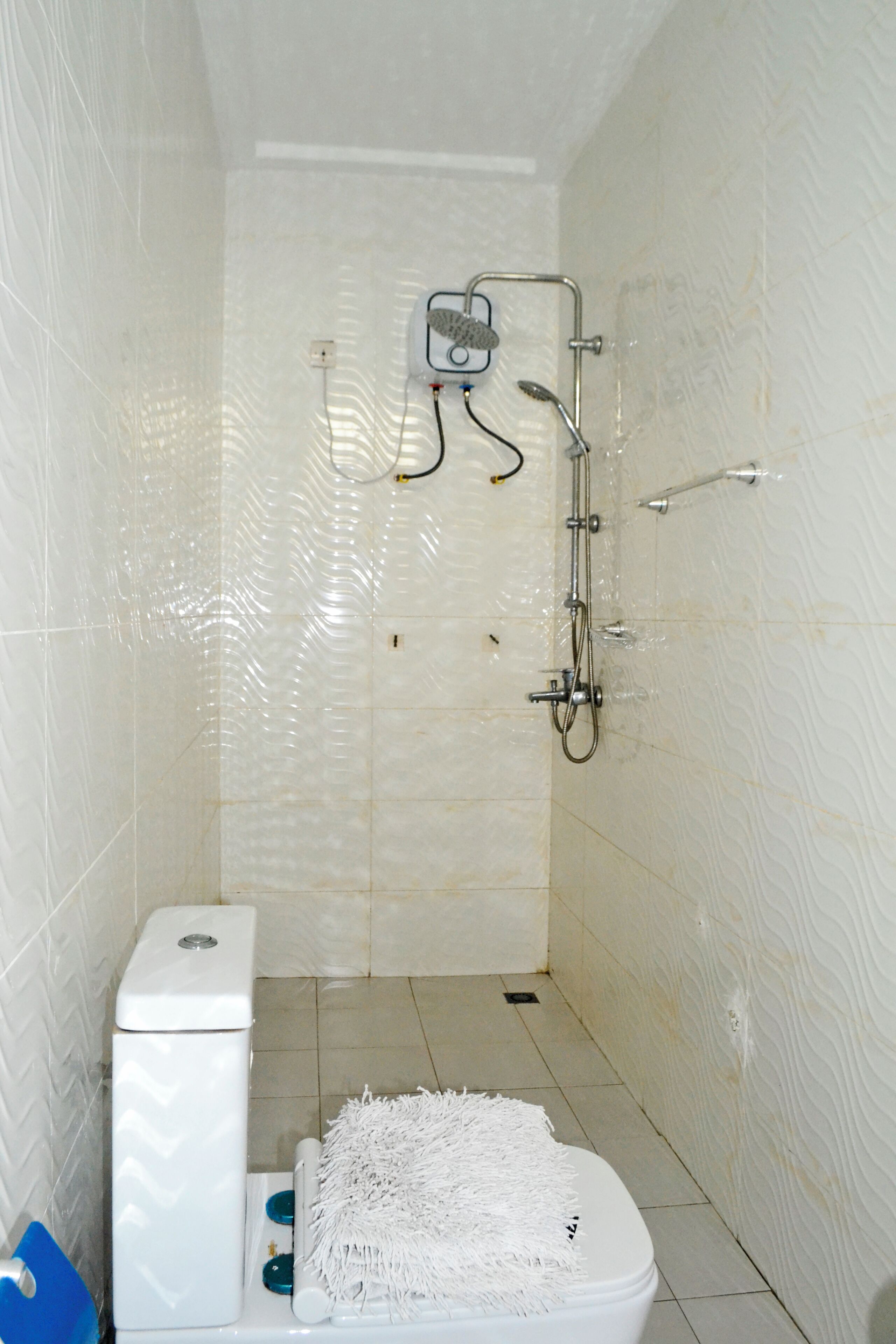 Ein Badezimmer mit Toilette, Dusche und gefliesten Wänden.