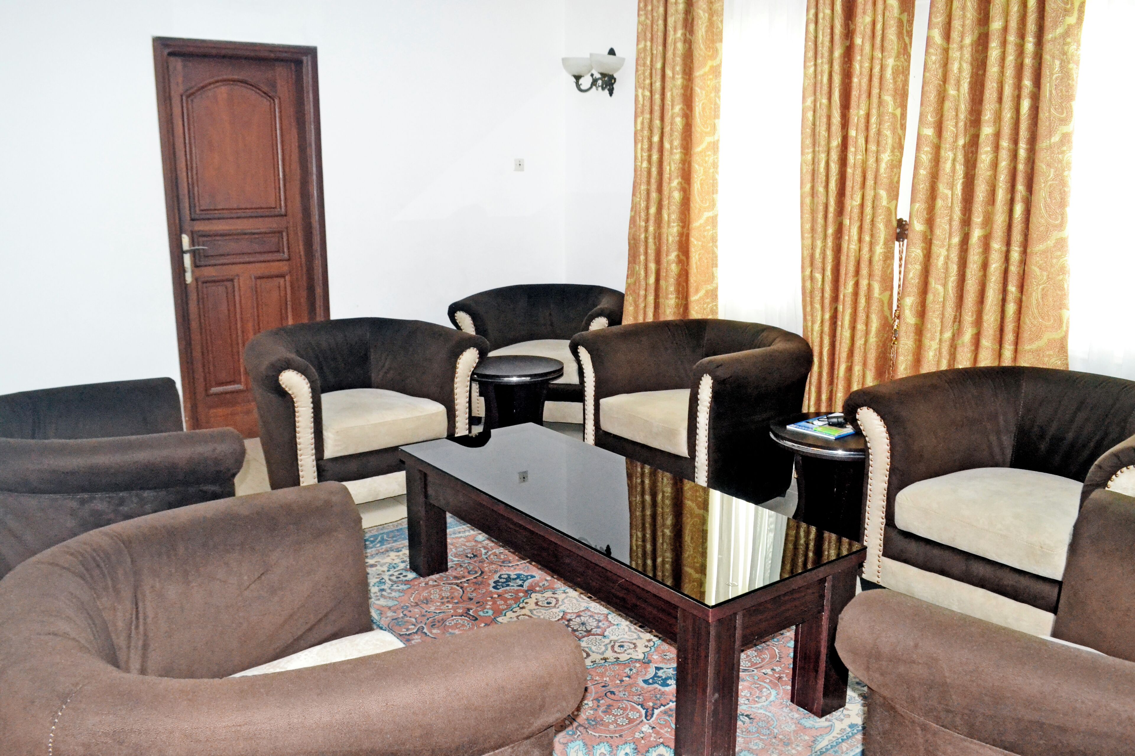 A room with a wooden door, a patterned carpet, and a table with four chairs.