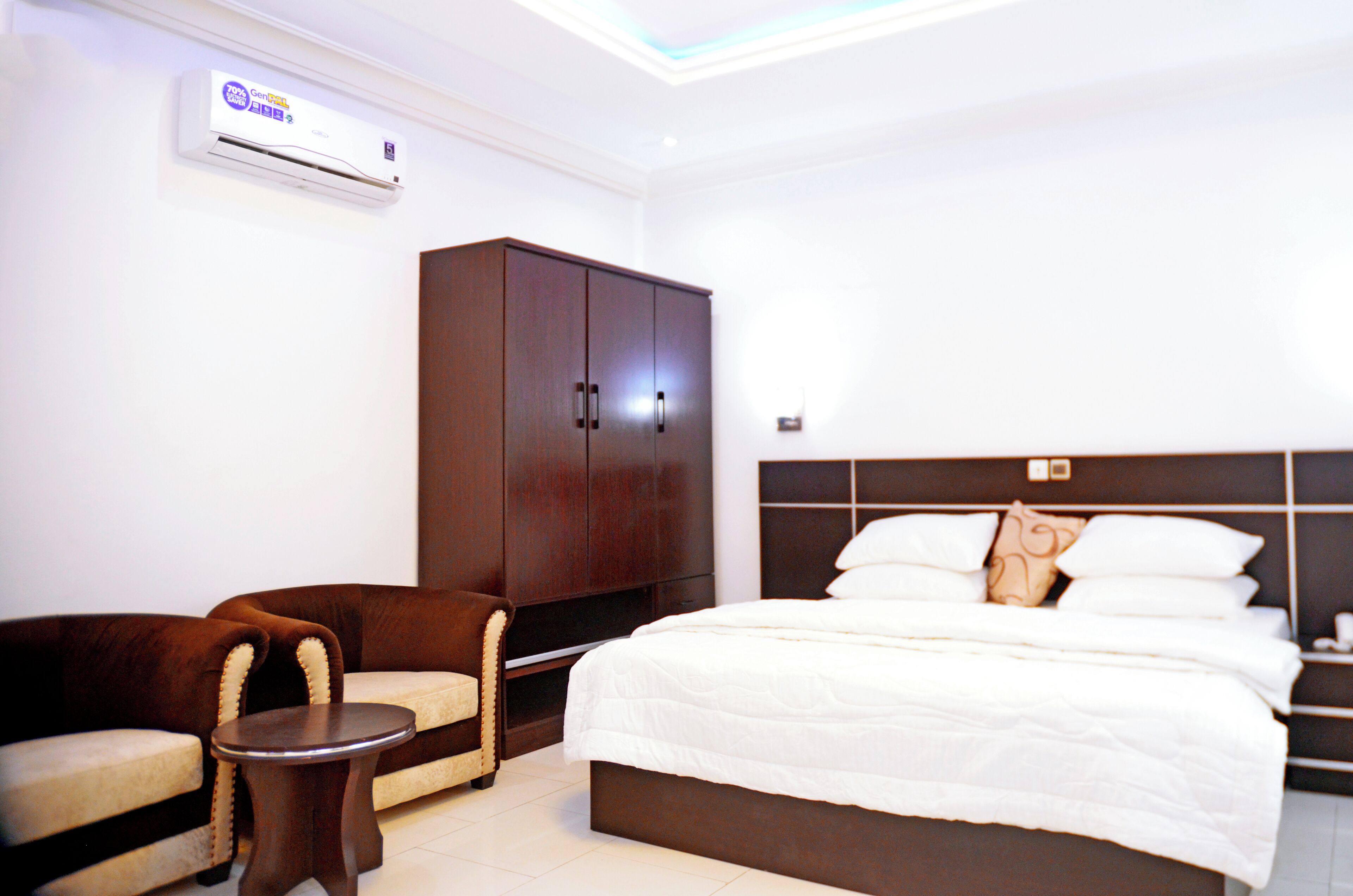 A hotel room with a bed, a wardrobe, a sofa, and a small table.