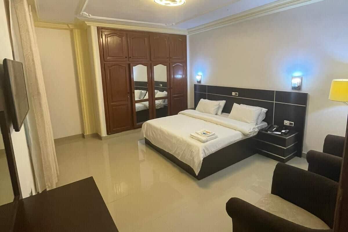 Une chambre d’hôtel comprenant un lit, des tables de chevet, une armoire et un coin salon.