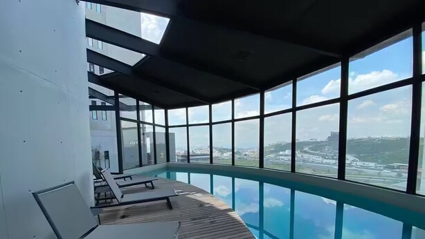 A modern indoor pool with clear views of the cityscape and ocean. - Adorable 1-bedroom apartment in tranquil Queretaro perfect for relaxing (QUERETARO)