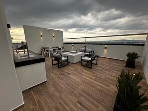 Eine Dachterrasse mit Sitzgelegenheit, einem kleinen Tisch und Blick auf die Stadt.