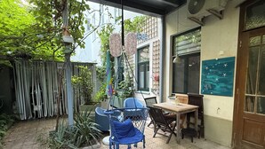 A patio area with a hanging chair, a table, and chairs. There is a potted plant and a hanging decoration.