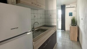 A kitchen with a white refrigerator, a sink, and wooden cabinets. - Apartments Natali (Gradac)