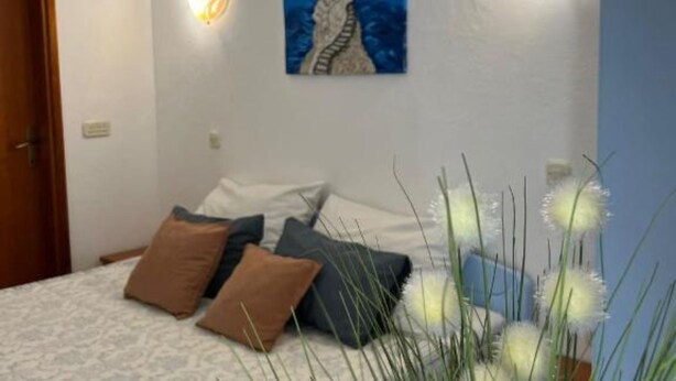A bedroom with a bed, pillows, a painting, and wall sconces. - Apartments Natali (Gradac)