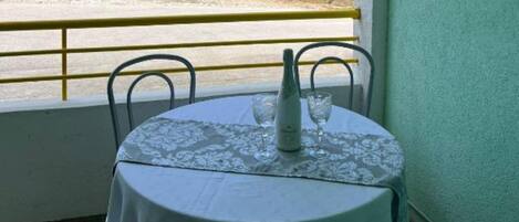 A table with a tablecloth and two chairs, a bottle, and a glass on the table.