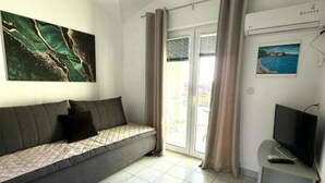 A modern living room with a sofa, a flat-screen TV, and a painting on the wall. - Apartments Natali (Gradac)