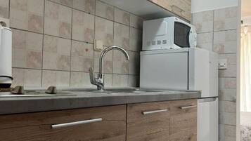 A kitchen with a tiled backsplash, a stainless steel sink, a microwave, and wooden cabinets.