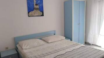 A bedroom with a bed, a wardrobe, a nightstand, and a painting on the wall.