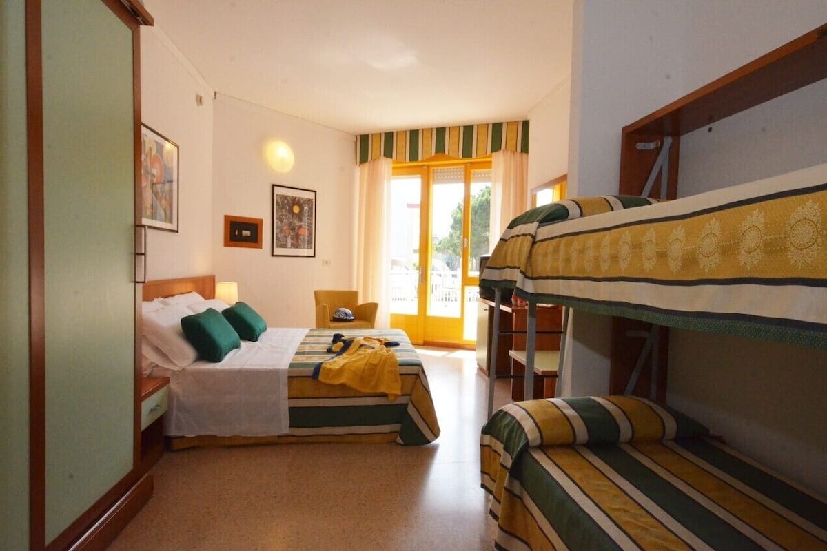 Una habitación con dos camas, una litera, una silla y una mesa.