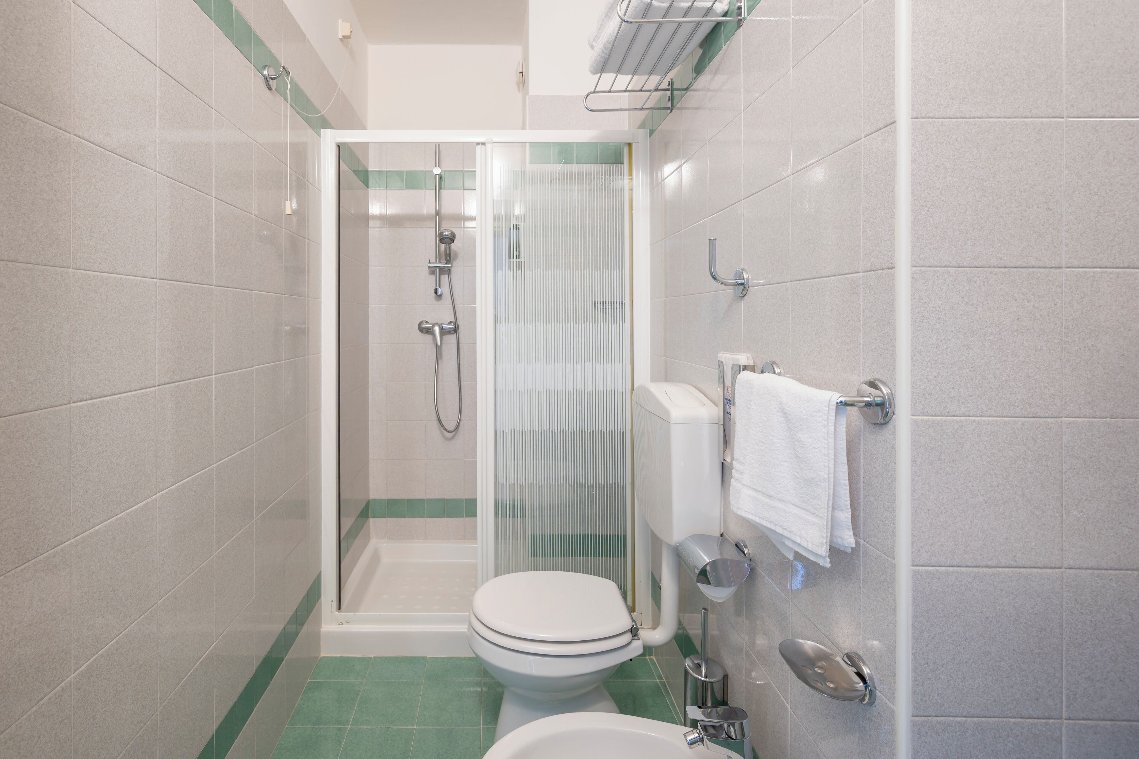 Une petite salle de bain avec des toilettes, une douche et un lavabo.