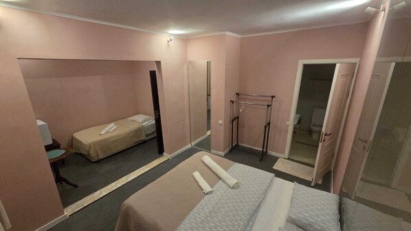 A small, pink-themed hotel room with a single bed, a small table, a chair, a wardrobe, and a mirror. - Walking distance to Cathedral, perfect place for wine lovers and thinkers. (T'bilisi)