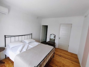 Ein Schlafzimmer mit Bett, Kommode, Spiegel und Tür.