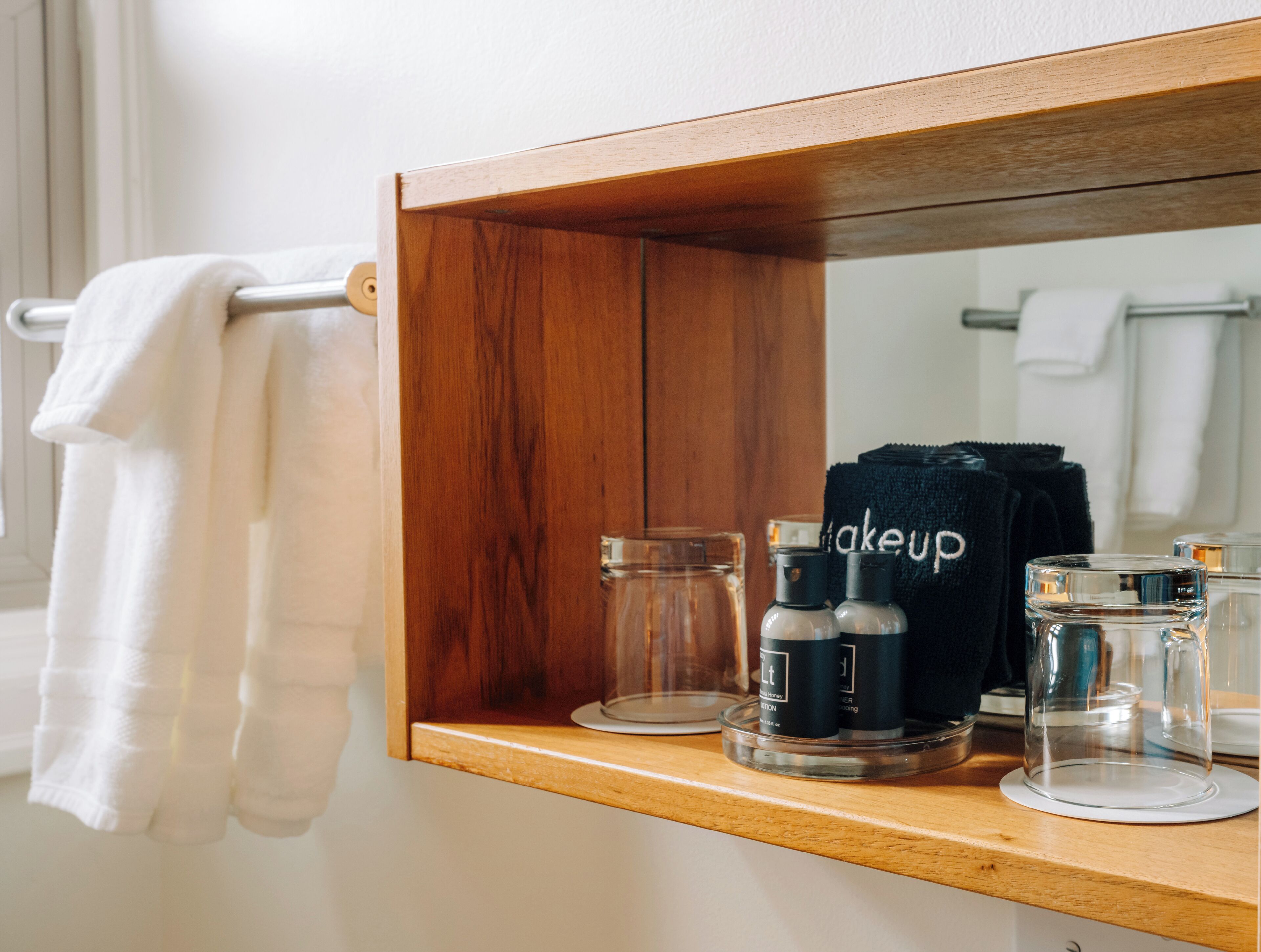 Un miroir à cadre en bois, avec une serviette suspendue à un porte-serviettes en métal situé à sa gauche.