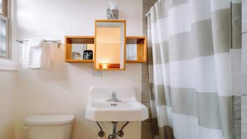 A bathroom with a toilet, a sink, a mirror, and a shower curtain.