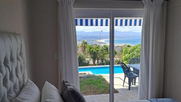 Un dormitorio con una cama grande, vistas a una piscina y zona exterior a través de una puerta corredera.