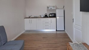 Un espacio habitable compacto con kitchenette, un sofá y un televisor de pantalla plana.
