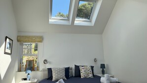 A bedroom with a bed, two windows, a bedside table, a lamp, and a mirror. - Birds Nest -  a cottage that sleeps 2 guests  in 1 bedroom (Gatehouse of Fleet)