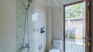 A bathroom with a shower, toilet, and a glass door leading to an outdoor area.