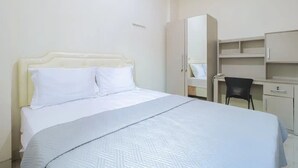 A bedroom with a bed, a desk, and a chair.