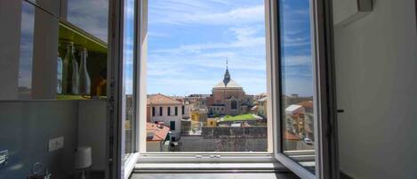 Un balcon offrant une vue dégagée sur le paysage urbain, avec notamment un bâtiment imposant doté d’un dôme et d’une flèche.