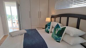A bedroom with a bed, a nightstand, a lamp, and a window with blinds.