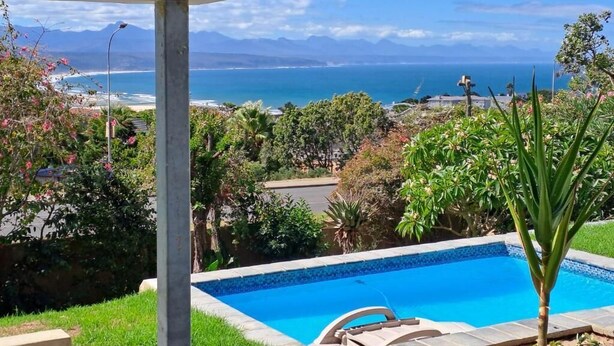 A pool with a view of the ocean and mountains.