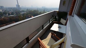 A balcony with a table and chairs, overlooking a cityscape with buildings and trees. - One bedroom apartment with panoramic view of Zagreb (Zagreb)